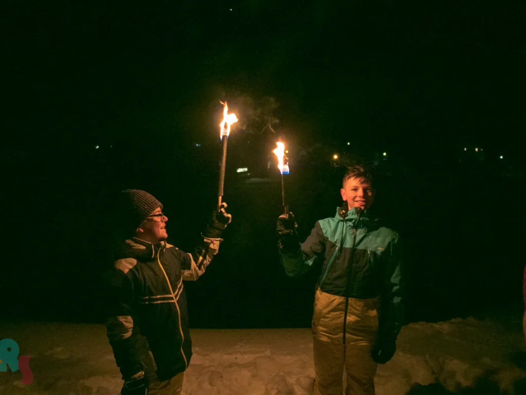 Zwei Jugendliche halten bei Nacht brennende Fackeln.